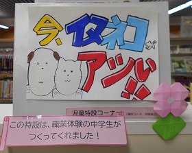 写真　児童特設コーナーに設置したポスターの写真。「今、イヌネコがアツい！！」という文字と、猫と犬のイラストが描かれています。