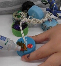 写真3　ペットボトルのふたにカラーペンで色を塗っている手元のアップ。