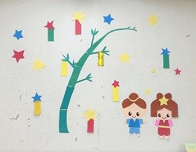 写真　笹のまわりを色とりどりの短冊と織姫と彦星が仲良く並ぶ壁面装飾。