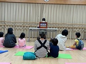 紙芝居『まんまるまんまたんたかたん』を親子で見ている様子。