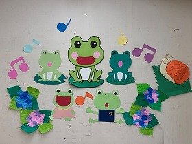 写真　あじさいの花の近くにいる5匹のかえると1匹のかたつむりの壁面装飾。