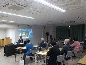 写真1　出口座の人形劇について解説する講師と、それを聞く参加者。