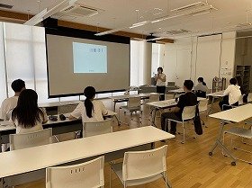 写真：健康医療情報講座「医療のお仕事発見ワークショップ」でスクリーンを見ながら講師のお話を聴いている参加者の様子。