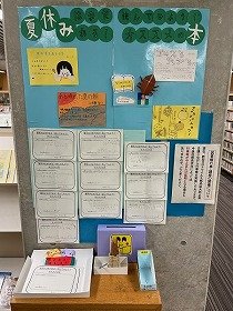 「夏休みはまだある！読んでみようオススメの本」の掲示板。YAサポーターのカラフルな紹介ポップと利用者が紹介してくれたオススメの本が書かれた紙を掲示している。